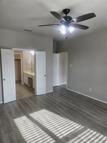 a view of an empty room and wooden floor and a kitchen