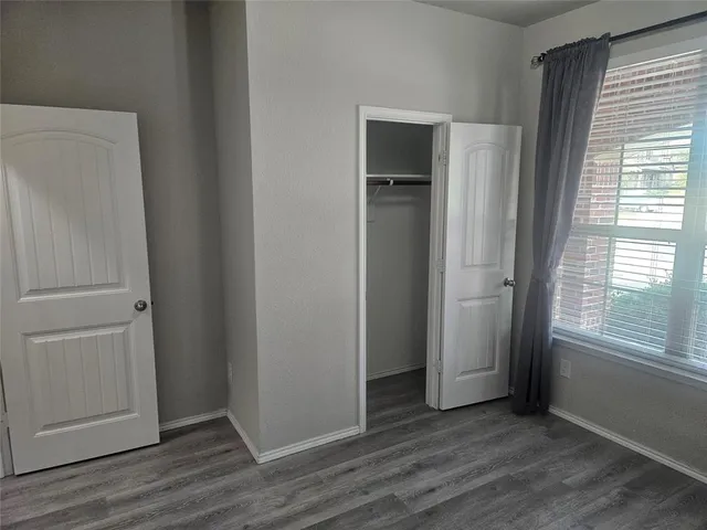 an empty room with wooden floor cabinet and windows