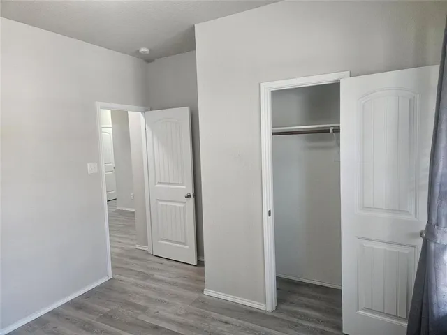 a view of an empty room with wooden floor and closet