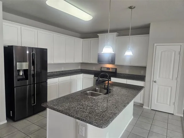 a kitchen with stainless steel appliances granite countertop a sink a refrigerator and a wooden cabinets