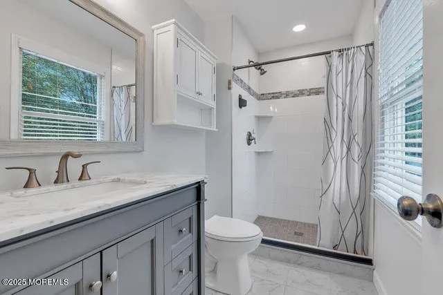 a bathroom with a granite countertop sink a toilet and shower