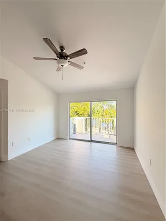 an empty room with windows and a ceiling fan