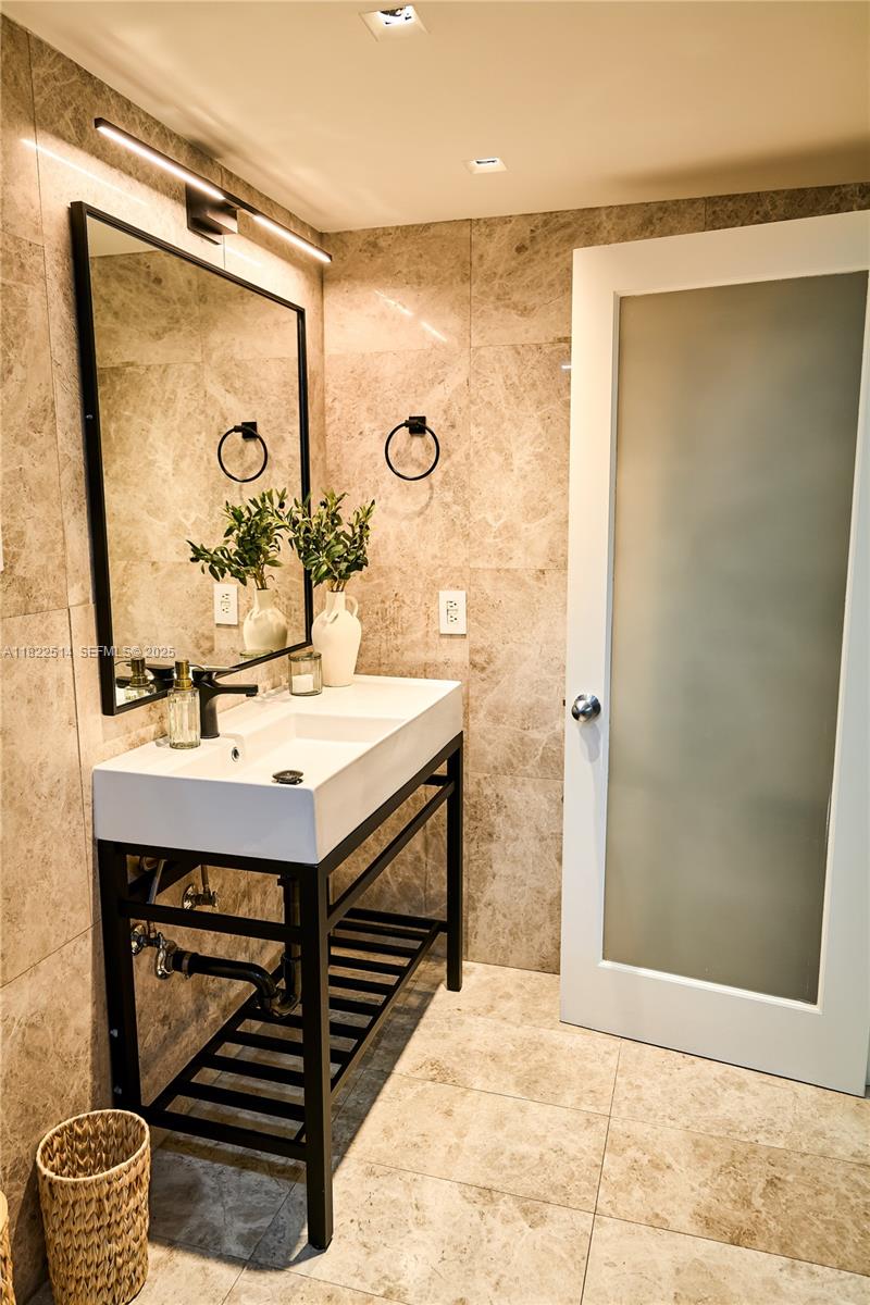 2301 Collins Avenue, Unit 329 Miami Beach, FL 33139 - Photo 21 of 47 a bathroom with a sink a mirror and a shower