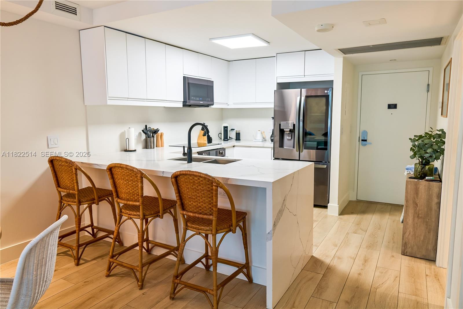 2301 Collins Avenue, Unit 329 Miami Beach, FL 33139 - Photo 6 of 47 a kitchen with stainless steel appliances granite countertop a refrigerator a stove a sink dishwasher and white cabinets with wooden floor