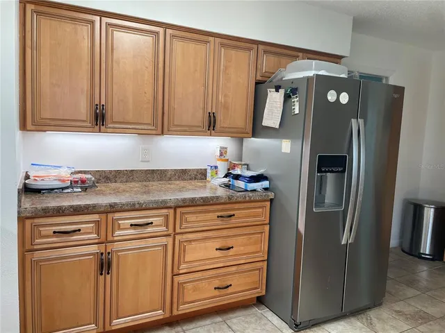 a kitchen with granite countertop a refrigerator and cabinets