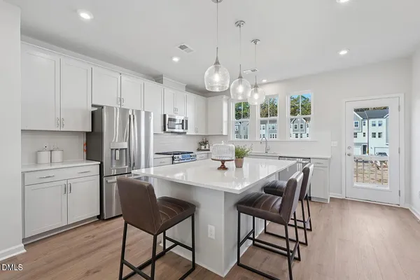 a kitchen with stainless steel appliances a table chairs refrigerator and sink