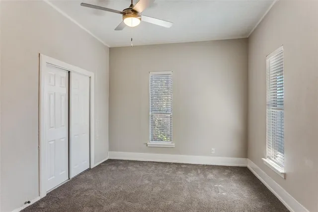 an empty room with windows and fan