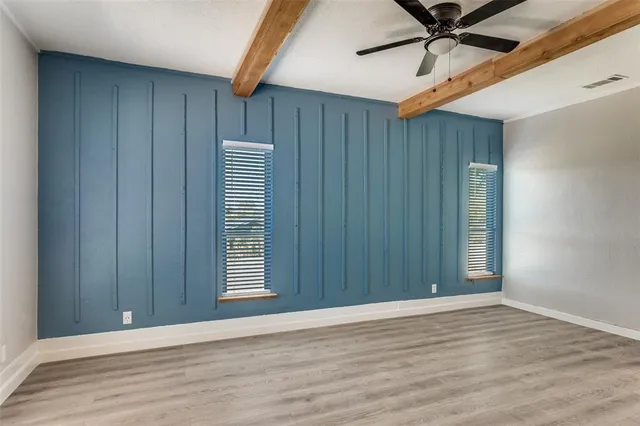 an empty room with wooden floor closet fan and windows