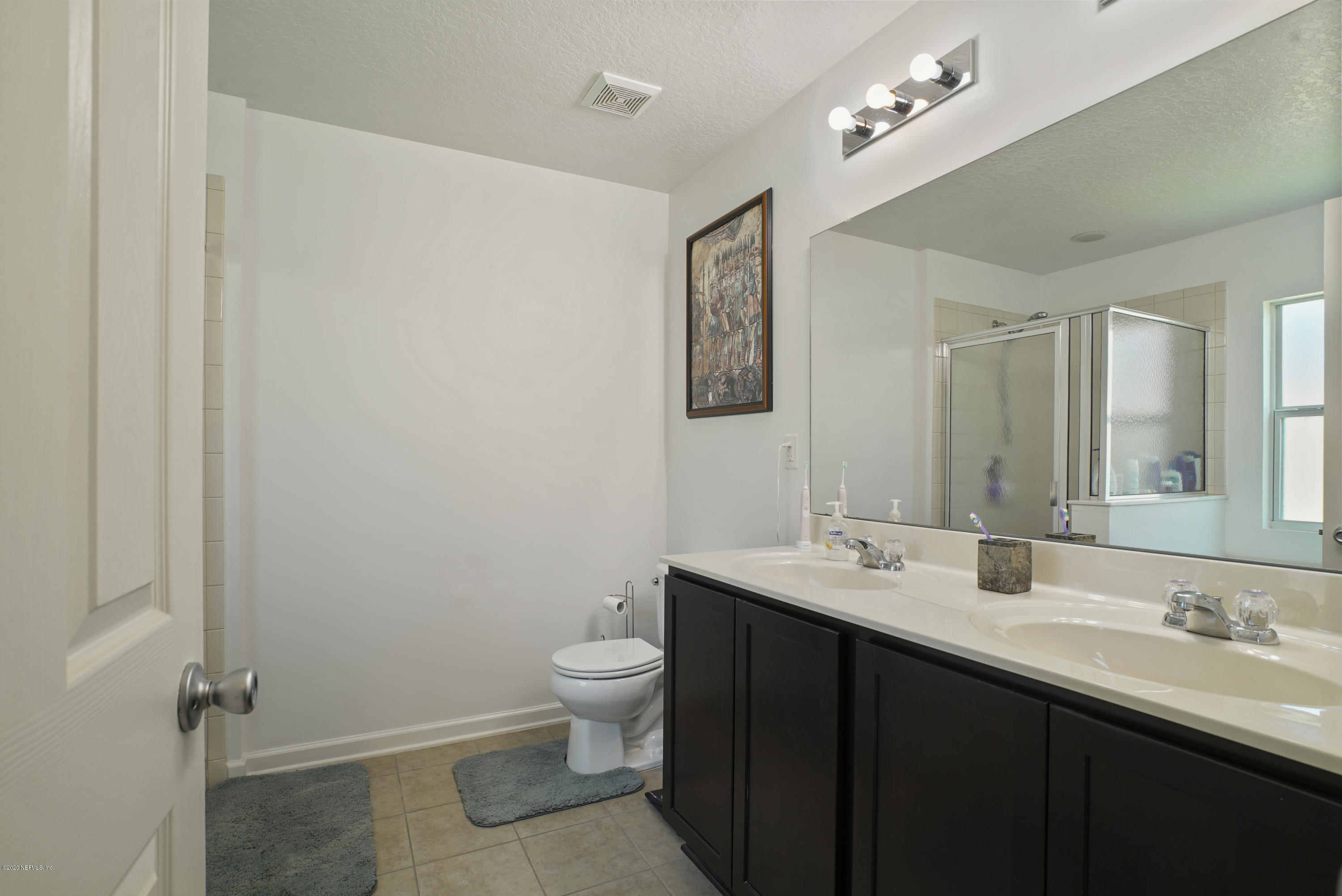 4447 Oak Moss Loop Middleburg, FL 32068 - Photo 18 of 36 a bathroom with a double vanity sink a toilet and a mirror