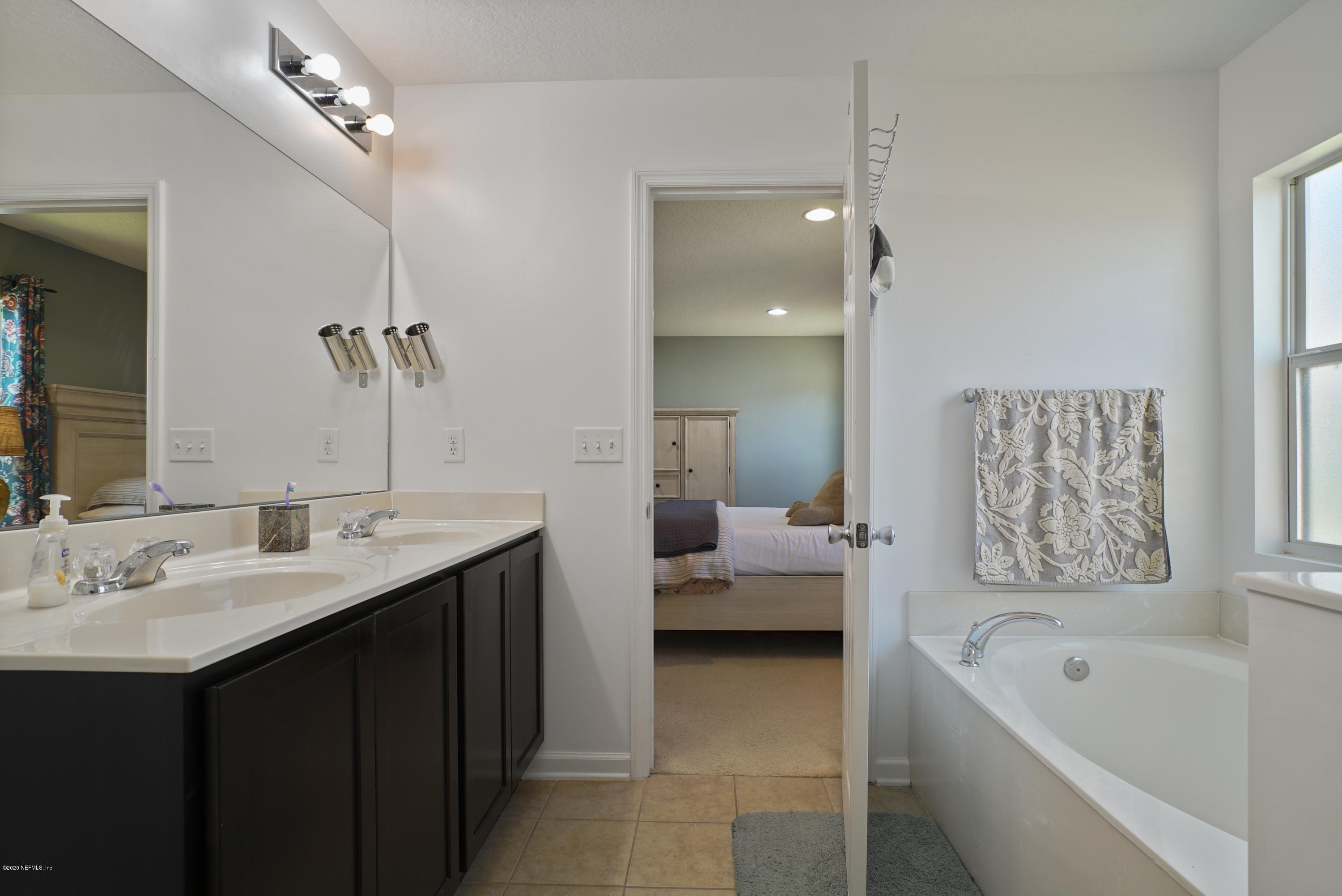 4447 Oak Moss Loop Middleburg, FL 32068 - Photo 19 of 36 a en suite spacious bathroom with a tub double sink window and mirror