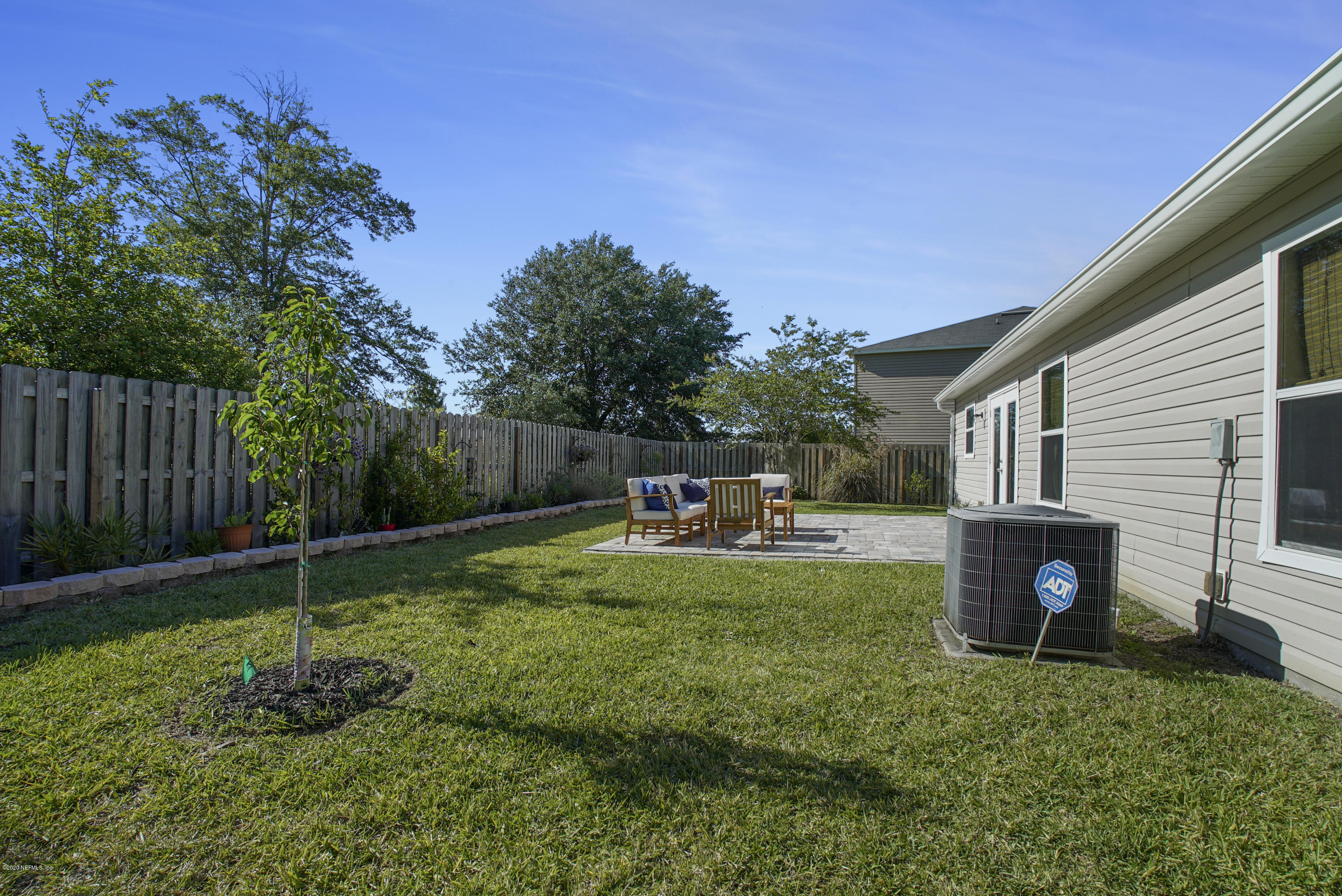 4447 Oak Moss Loop Middleburg, FL 32068 - Photo 32 of 36 a view of a backyard with table and chairs potted plants and wooden fence