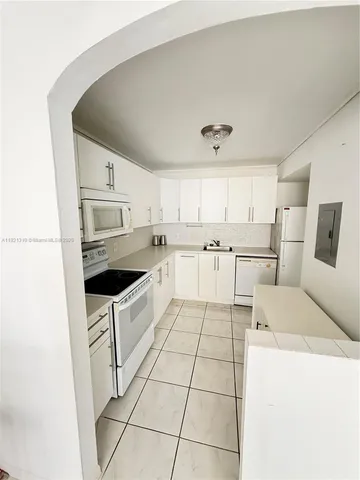 a kitchen with a sink a stove and white cabinets