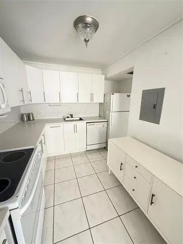 a kitchen with white cabinets a stove a sink and dishwasher