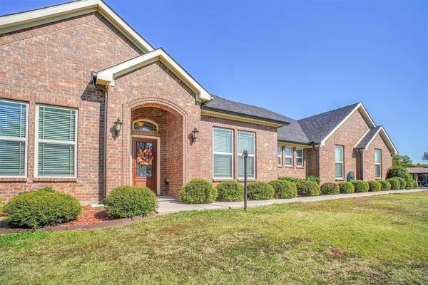 a view of a brick house with a large windows and a yard