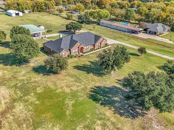 an aerial view of residential houses with outdoor space and trees