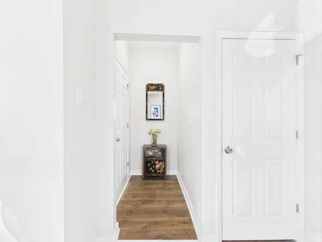 a view of a hallway with wooden floor and a bathroom