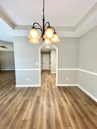 a view of a big room with wooden floor windows and a chandelier