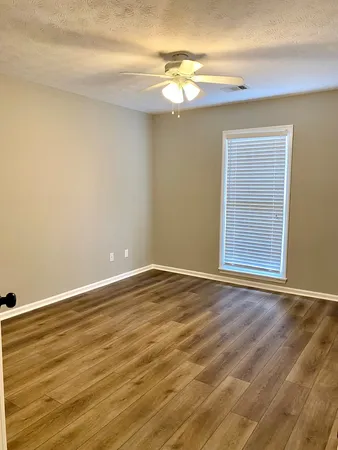 a view of an empty room with window and wooden floor