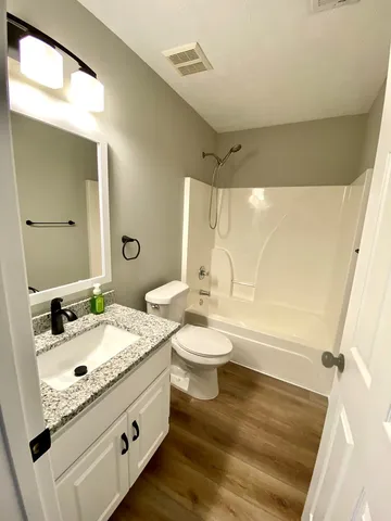 a bathroom with a granite countertop sink mirror vanity and toilet