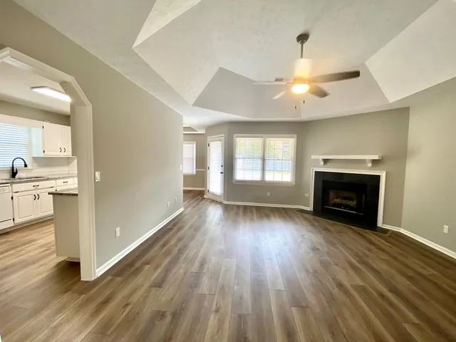 an empty room with wooden floor fireplace and windows