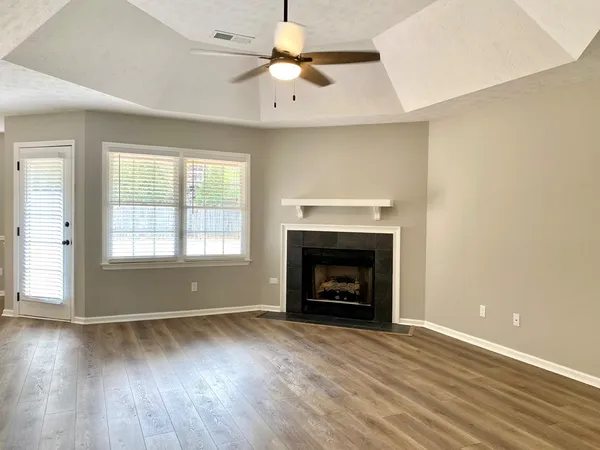 an empty room with windows a fireplace and wooden floor
