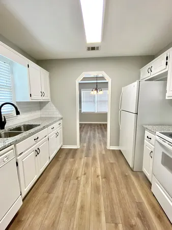 a kitchen with granite countertop white cabinets and white appliances