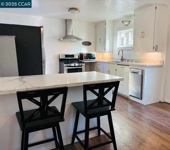 a kitchen with stainless steel appliances kitchen island a table chairs and a refrigerator