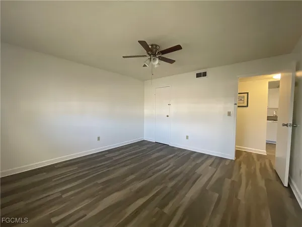 an empty room with wooden floor and a ceiling fan