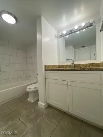 a bathroom with a granite countertop sink a toilet and a bathtub