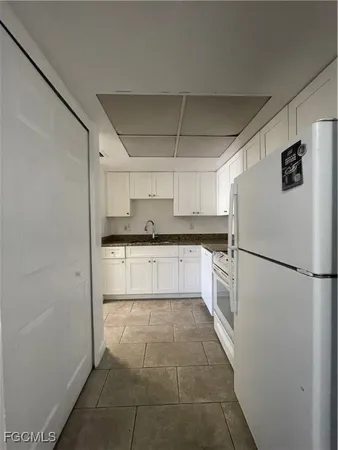 a kitchen with a refrigerator and white cabinets