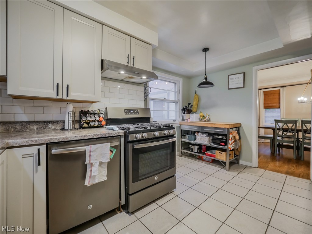 2378 Charney Road Cleveland, OH 44118 - Photo 9 of 28 Kitchen with a tray ceiling, light hardwood / wood-style floors, tasteful backsplash, stainless steel appliances, and pendant lighting