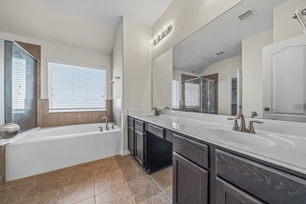a bathroom with a granite countertop bathtub a double vanity sink and mirror