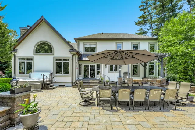a view of a white house with table and chairs under an umbrella