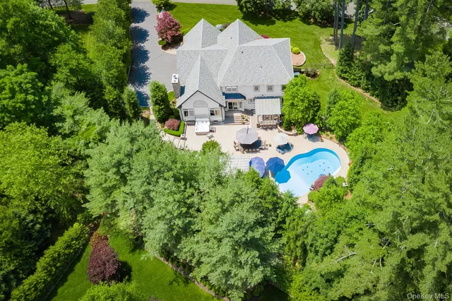an aerial view of a house with outdoor space and trees all around