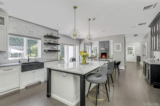 a kitchen with stainless steel appliances kitchen island granite countertop a table chairs and white cabinets