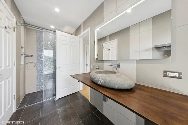 a bathroom with a granite countertop sink a mirror and shower