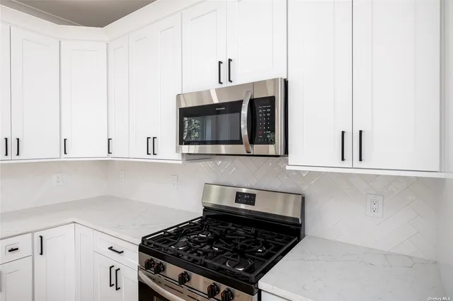 a kitchen with stainless steel appliances a stove and white cabinets