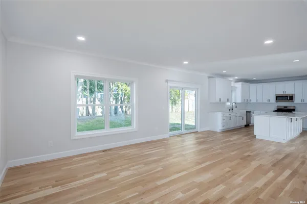 a view of an empty room with kitchen and window