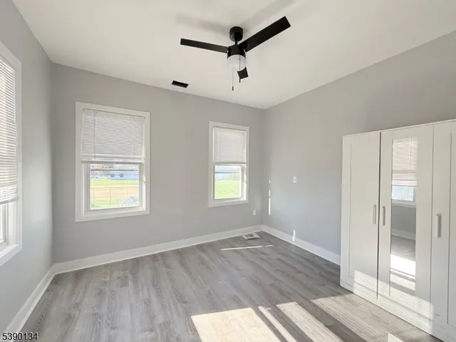 a view of empty room with wooden floor and fan