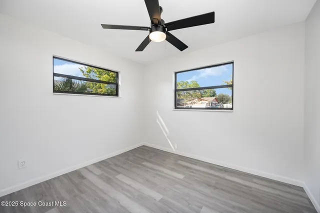 an empty room with wooden floor and ceiling fan