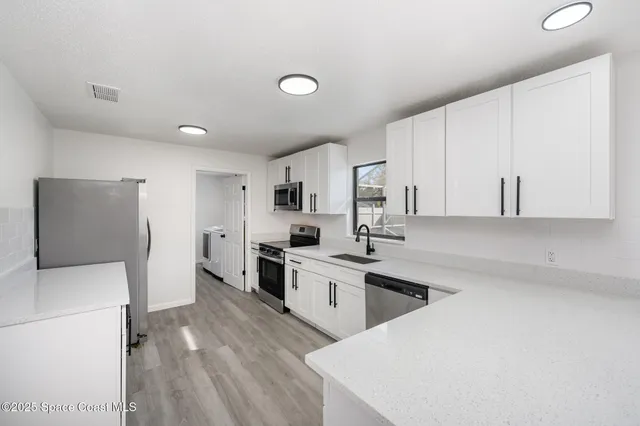 a kitchen with white cabinets and white appliances