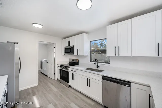 a kitchen with white cabinets and stainless steel appliances