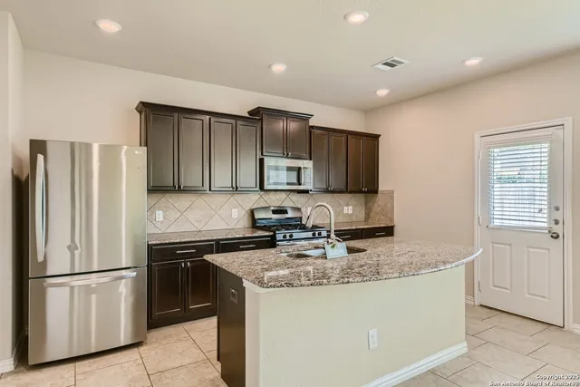 a kitchen with stainless steel appliances granite countertop a refrigerator a sink a stove a microwave and island