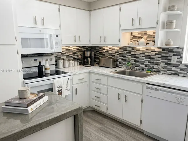 a kitchen with white cabinets and appliances