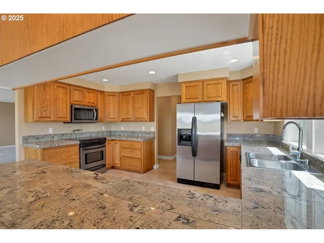 a kitchen with stainless steel appliances granite countertop a refrigerator a stove top oven a sink and dishwasher