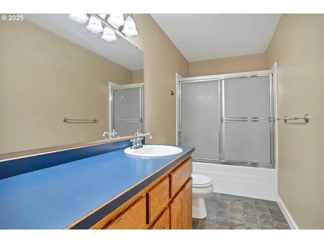 a bathroom with a sink a toilet a mirror and shower