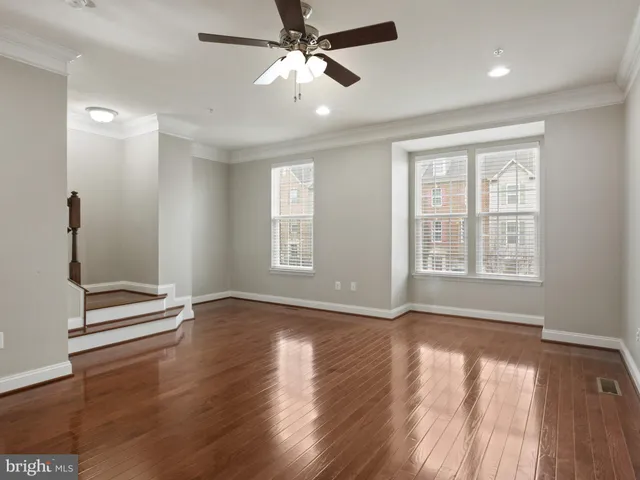 an empty room with wooden floor fan and windows