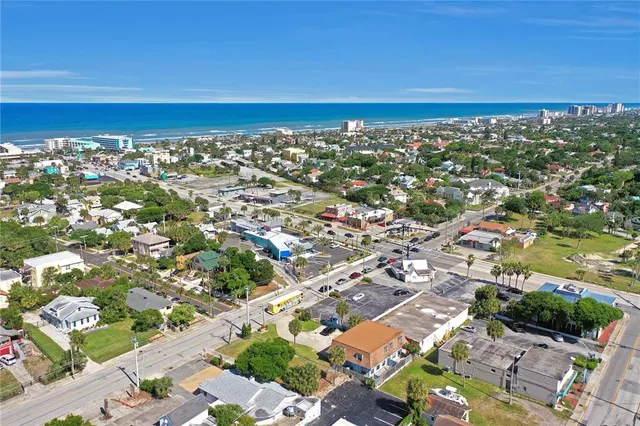 an aerial view of a city with lots of residential buildings and ocean view in back