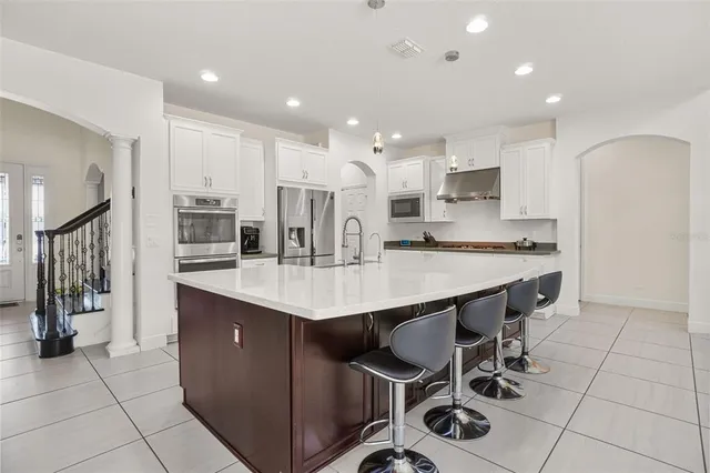 a kitchen with stainless steel appliances a dining table chairs and stove