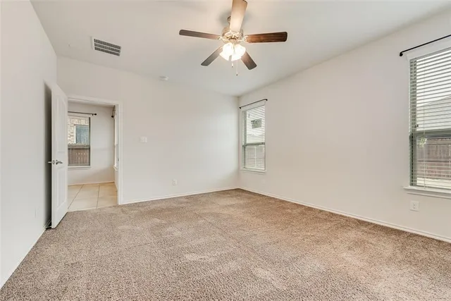 an empty room with fan and windows
